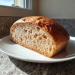 A cross-section of a freshly baked beer bread loaf showing a soft, airy crumb texture on a white plate.