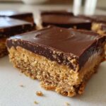 A close-up of a single square of Buckeye Graham Crackers bar showing the crumbly base, peanut butter layer, and smooth chocolate topping.
