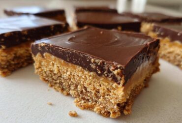A close-up of a single square of Buckeye Graham Crackers bar showing the crumbly base, peanut butter layer, and smooth chocolate topping.