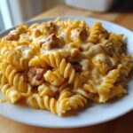 A close-up of cheesy chicken pasta made with fusilli noodles and topped with melted cheese.