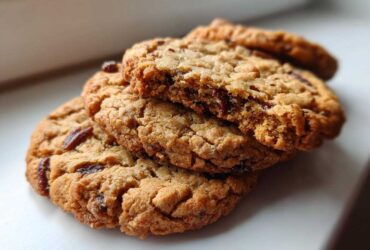 A stack of three golden brown butter pecan cookies, one broken open to show the chewy interior.
