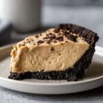 Close-up of a thick slice of creamy peanut butter pie with a dark chocolate crumb crust.