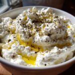 A close-up of creamy, fluffy whipped feta dip topped with olive oil and dried herbs.