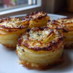 Four perfectly browned, individual potato stacks made from thinly sliced potatoes, baked until crispy.