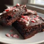 Close-up of fudgy peppermint brownies topped with chocolate frosting and crushed candy canes.