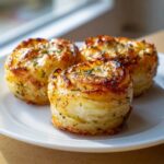 Three perfectly baked potato stacks showing layers and golden brown edges, sprinkled with herbs.