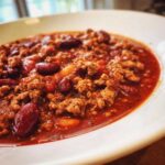Close-up of a rich, red bowl of high protein chili loaded with ground meat and kidney beans.