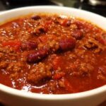 Close-up of a hearty bowl of rich, red high protein chili loaded with ground meat and kidney beans.
