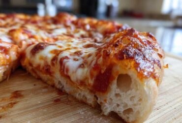 Close-up of a thick, airy slice of homemade pizza showing melted cheese and bubbly crust.