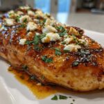 A juicy chicken breast covered in a shiny hot honey glaze, topped with crumbled feta cheese and fresh parsley.