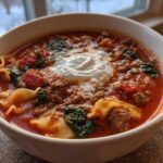 Close-up of a bowl of rich instant pot lasagna soup topped with a dollop of ricotta cheese.
