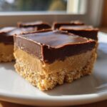 Close-up of three delicious lunch lady peanut butter bars with a chocolate topping on a white plate.