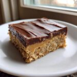 A single square of lunch lady peanut butter bars with a thick chocolate topping on a white plate.