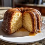 A moist, golden Bacardi Rum Cake, cut in half to show the crumb, heavily drizzled with a rum glaze.
