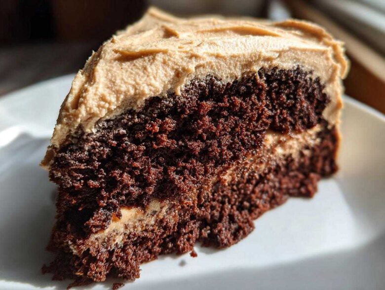 Close-up of a moist, dark slice of gingerbread cake layered with light brown frosting.