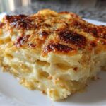 A close-up slice of creamy potatoes au gratin featuring layered potatoes and a deeply browned, cheesy top crust.