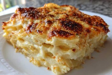 A close-up slice of creamy potatoes au gratin featuring layered potatoes and a deeply browned, cheesy top crust.
