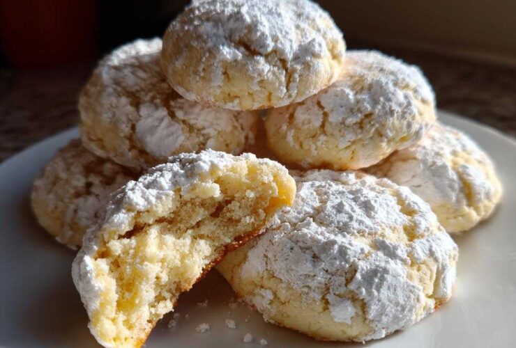 A stack of soft, powdered sugar-dusted cool whip cookies, with one cookie broken open showing the texture.
