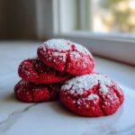 A stack of vibrant red velvet cake mix cookies dusted heavily with white powdered sugar.