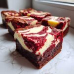 A close-up of a rich, marbled red velvet cheesecake brownie square with a dense, fudgy base.