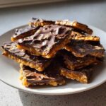 A pile of broken pieces of rich saltine cracker toffee featuring a thick layer of caramel and dark chocolate topping.