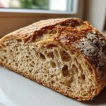Close-up of the interior crumb structure of a freshly baked whole wheat bread loaf, showing open air pockets.