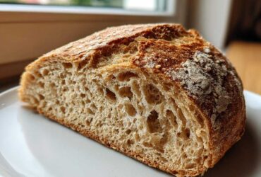 Close-up of the interior crumb structure of a freshly baked whole wheat bread loaf, showing open air pockets.