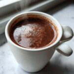 Close-up of a steaming white mug filled with rich, dark french hot chocolate.