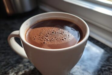 Close-up of a white mug filled with rich, dark french hot chocolate topped with small bubbles.