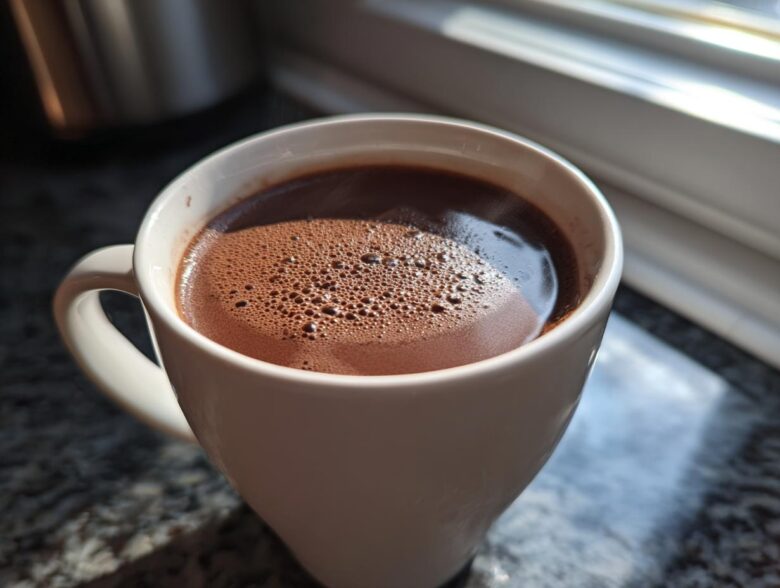 Close-up of a white mug filled with rich, dark french hot chocolate topped with small bubbles.