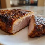 Close-up of juicy, perfectly cooked air fryer pork chops, sliced to show the tender interior and seasoned crust.