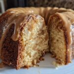 Close-up of a slice cut from a moist apple bundt cake topped with dripping caramel glaze.
