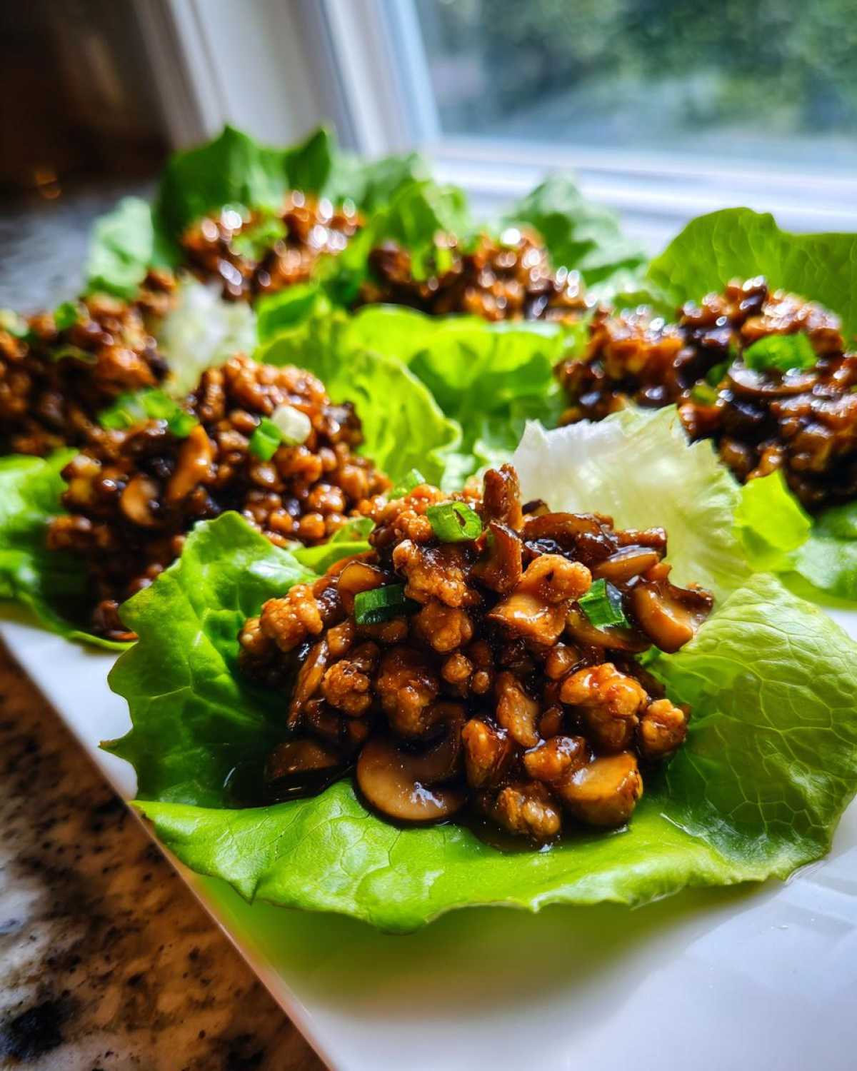 Close-up of several finished chicken lettuce wraps filled with savory ground chicken and mushrooms, ready to serve.