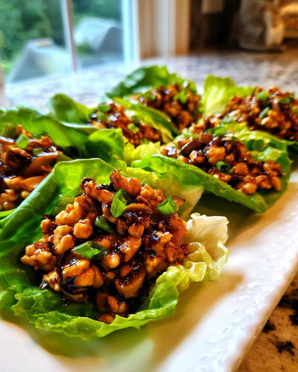 Close-up of several delicious chicken lettuce wraps filled with savory ground chicken mixture and topped with green onions.