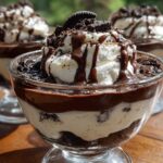 Close-up of a single serving of Baileys Chocolate Cheesecake Trifle topped with whipped cream and chocolate drizzle.