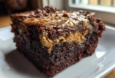 Close-up of a rich, fudgy banana bread brownies square with a gooey peanut butter swirl on top, served on a white plate.