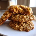 A stack of four soft, chewy banana oatmeal cookies piled on a white plate.