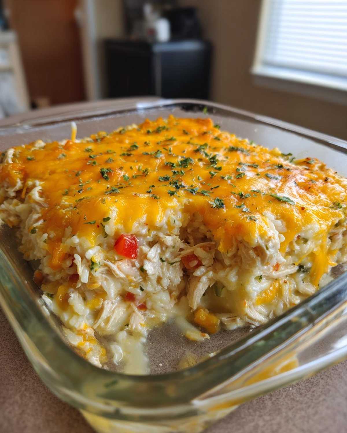 A close-up of a creamy chicken and rice casserole topped with melted cheddar cheese and parsley.