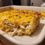 A close-up view of a hearty slice of chicken and rice casserole topped with melted cheddar cheese.