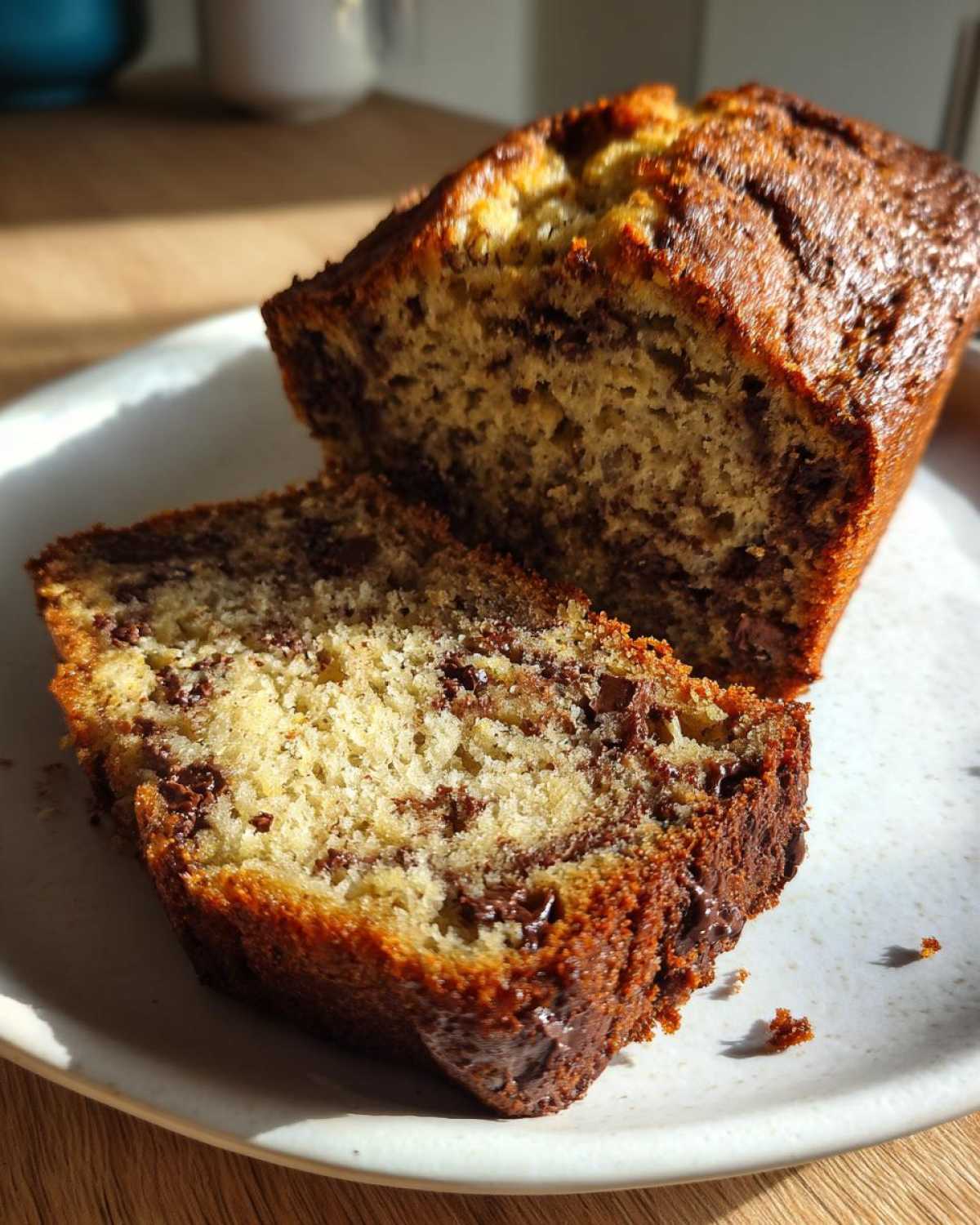 Close-up of a slice of moist chocolate chip banana bread recipe loaf on a white plate.