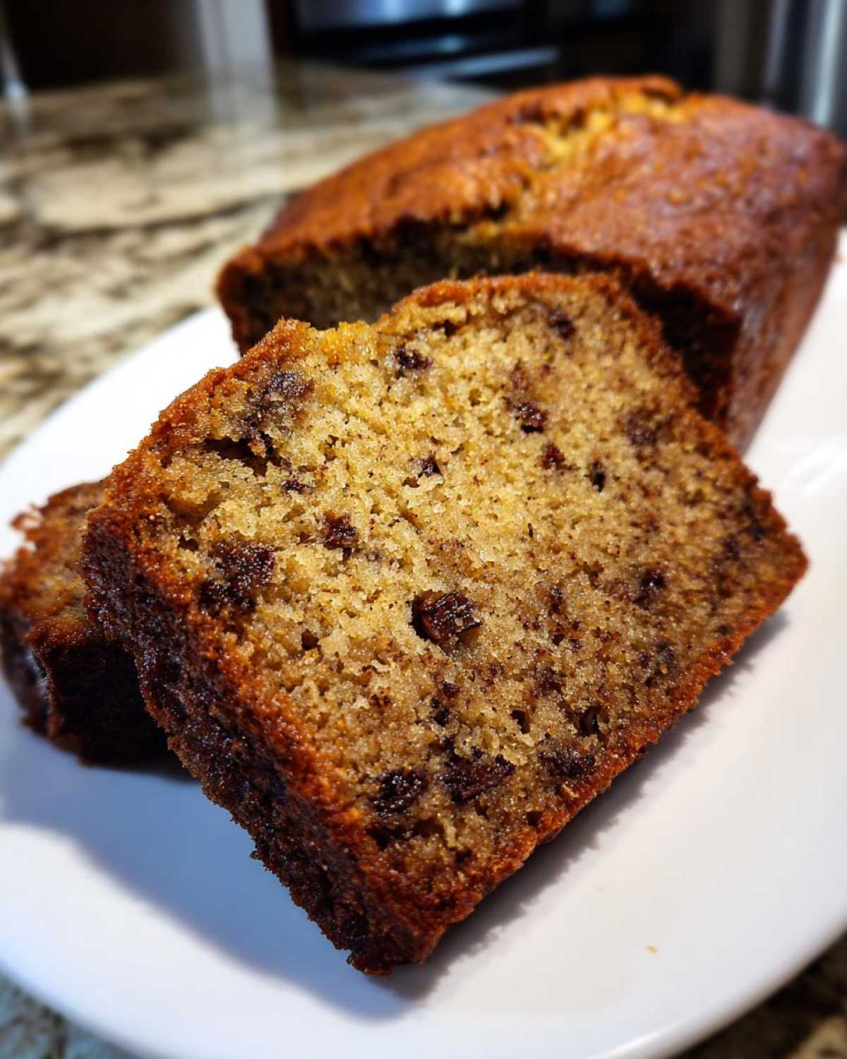 Close-up of moist chocolate chip banana bread recipe slices on a white plate.