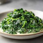 A close-up shot of vibrant green spinach coated in a rich, creamy sauce, showcasing the perfect creamed spinach recipe.