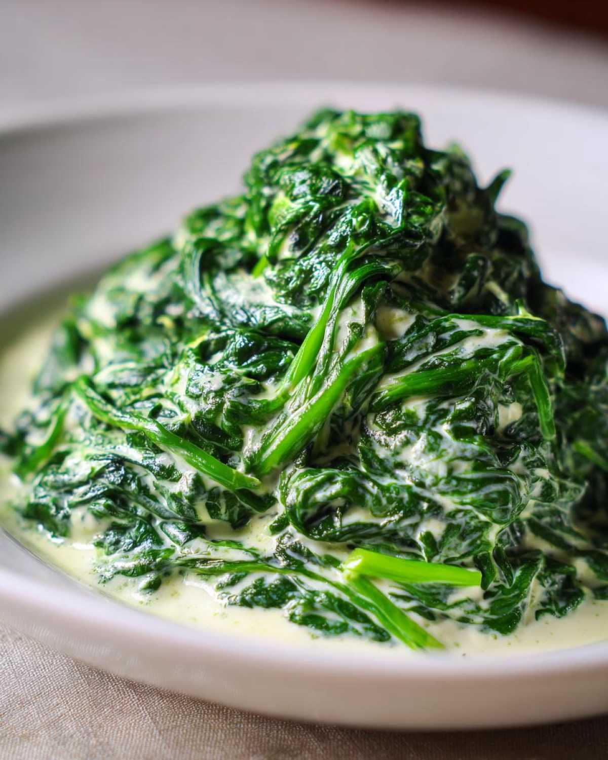 Close-up of vibrant green spinach coated in a rich white sauce, showcasing the finished creamed spinach recipe.