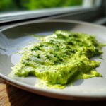 Close-up of vibrant green, creamy avocado sauce drizzled on a light plate, garnished with fresh herbs.