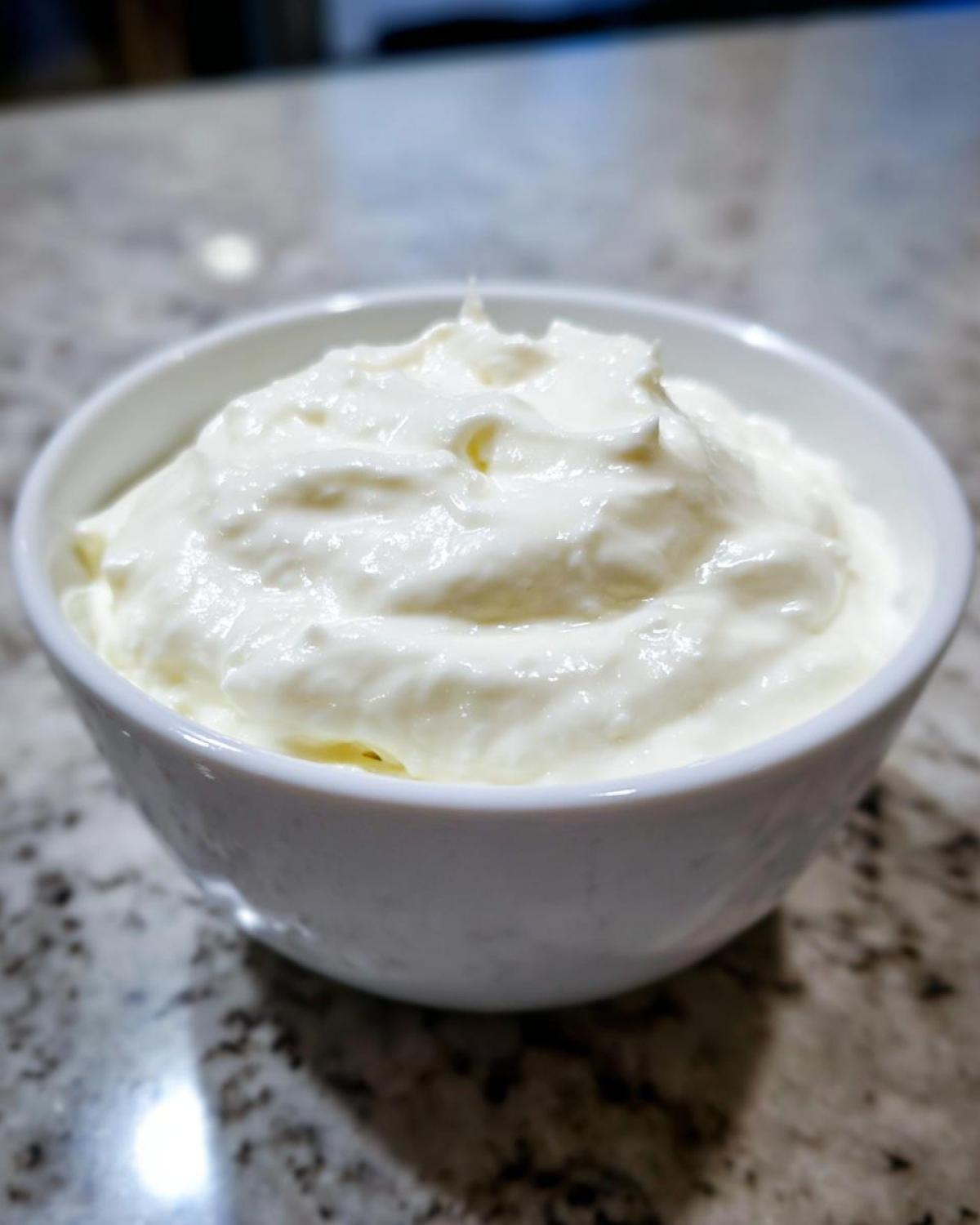 Close-up of a white bowl filled with creamy white sauce, the base for horseradish sauce.