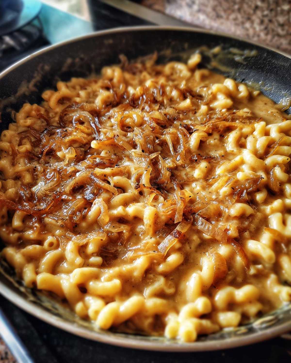 Close-up of creamy french onion pasta made with macaroni noodles and topped with caramelized onions in a skillet.