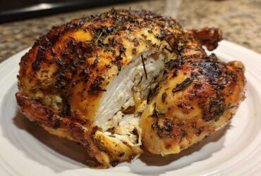 A whole roasted spatchcock chicken, cut open to show juicy white meat and crispy, herb-rubbed skin.
