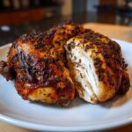 Close-up of juicy spatchcock chicken, showing crispy, herb-rubbed skin and moist white meat inside.