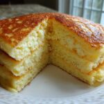 A stack of incredibly fluffy pancakes cut in half to show the airy interior texture, demonstrating amazing lift.