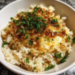 Close-up of a bowl of french onion butter rice topped with caramelized onions and fresh parsley.